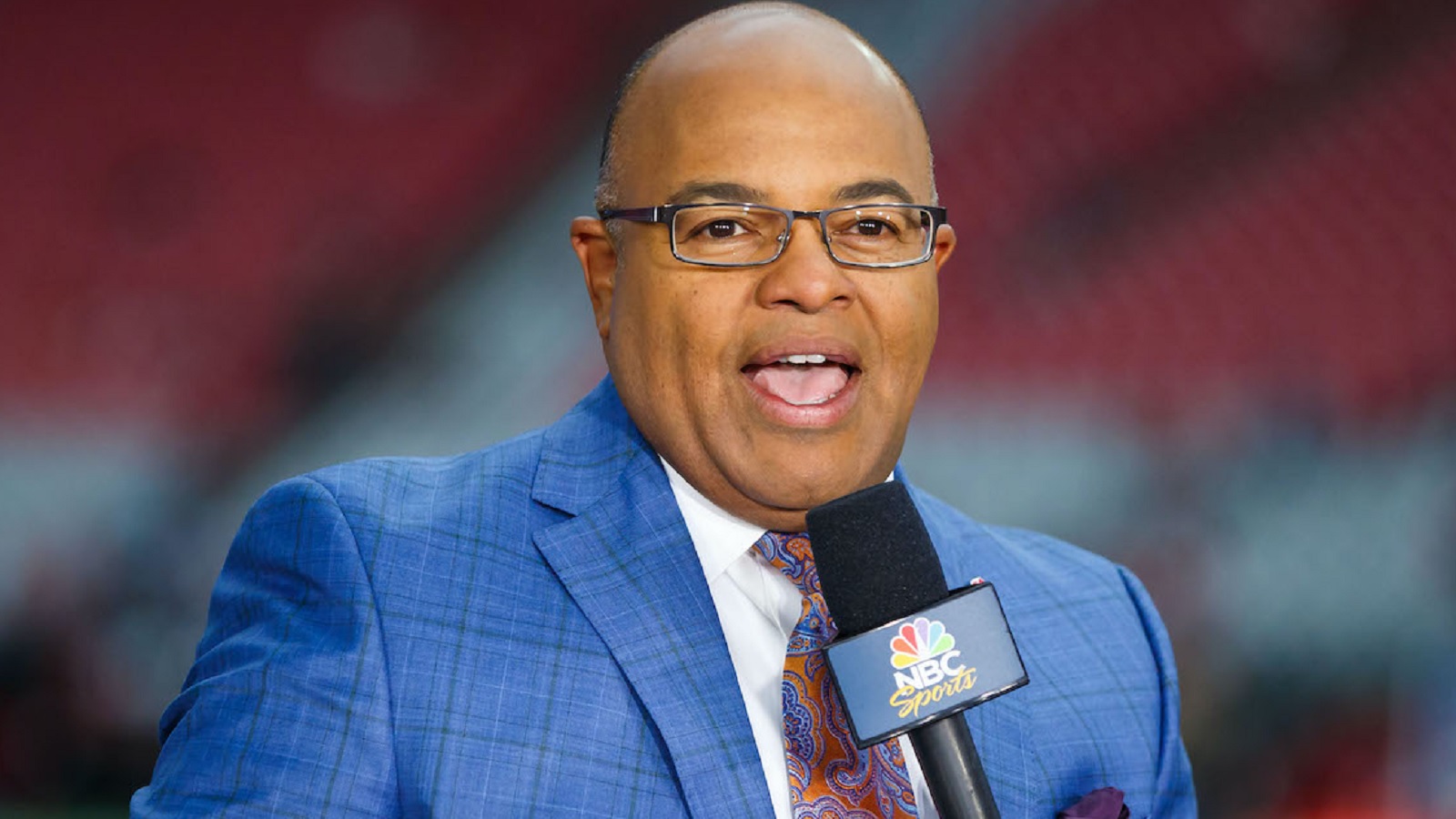 Mike Tirico holding a microphone